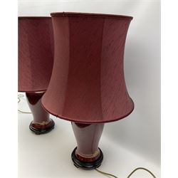 Pair of dark red table lamps in baluster form with a round wooden base, with matching shades, H69cm.  