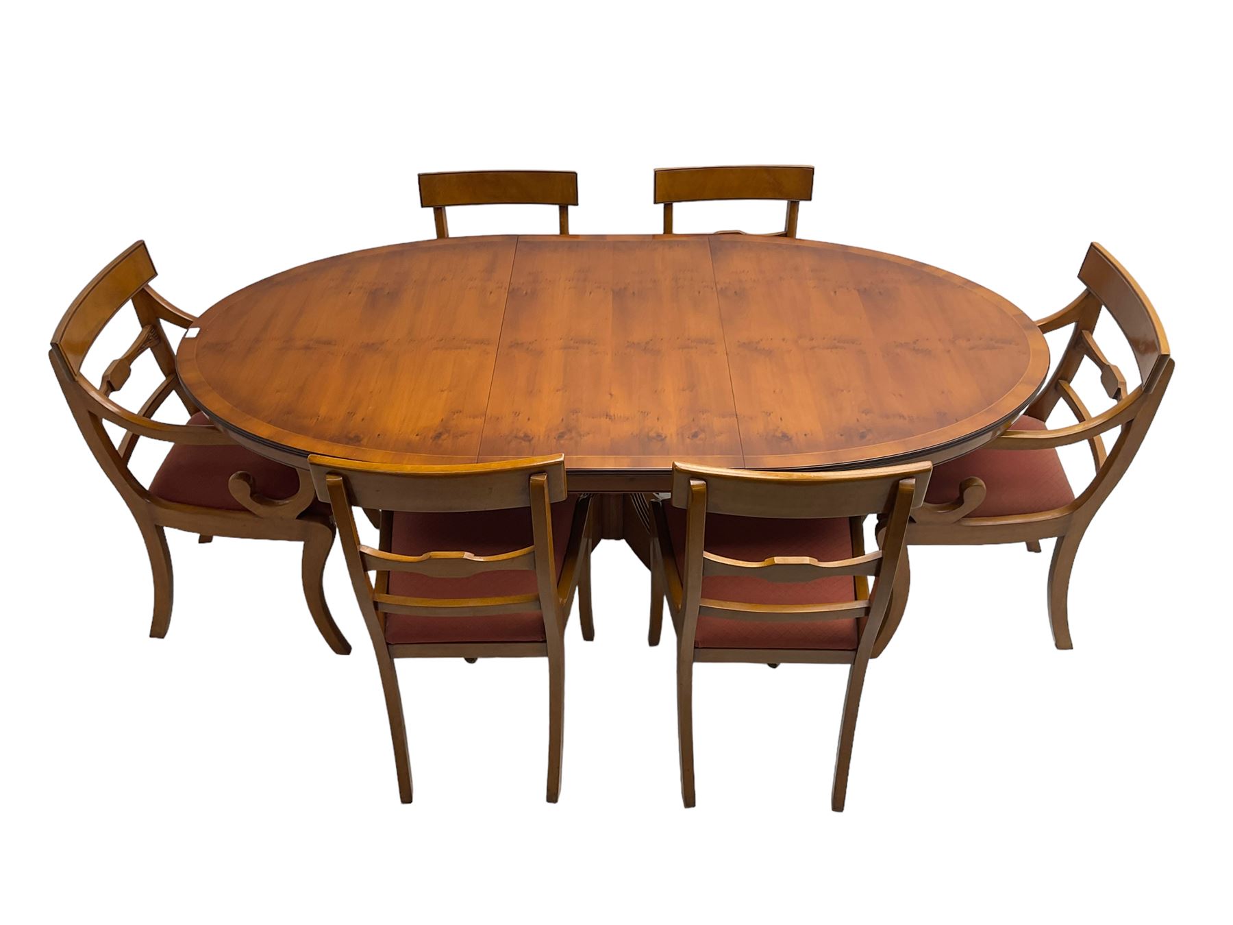 Regency design yew wood dining table, oval cross-banded top with reeded edge, raised on turned pedestal with reeded sabre supports terminating in brass hairy paw feet and castors (W138cm D100cm H75cm); and Rackstraw - set six (4+2) Regency design dining chairs with red drop-in seats (W50cm H86cm)