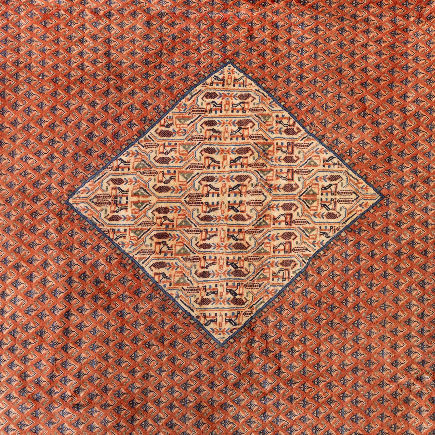 North West Persian Boteh-Mir hand-knotted rug, madder red field decorated with an all-over lattice of small boteh motifs and a central stepped lozenge medallion with repeating stylized boteh and geometric devices, spandrels similarly worked, with multiple narrow borders of floral and geometric bands, in tones of madder red, indigo blue, ivory, and soft green, with cotton fringe ends 