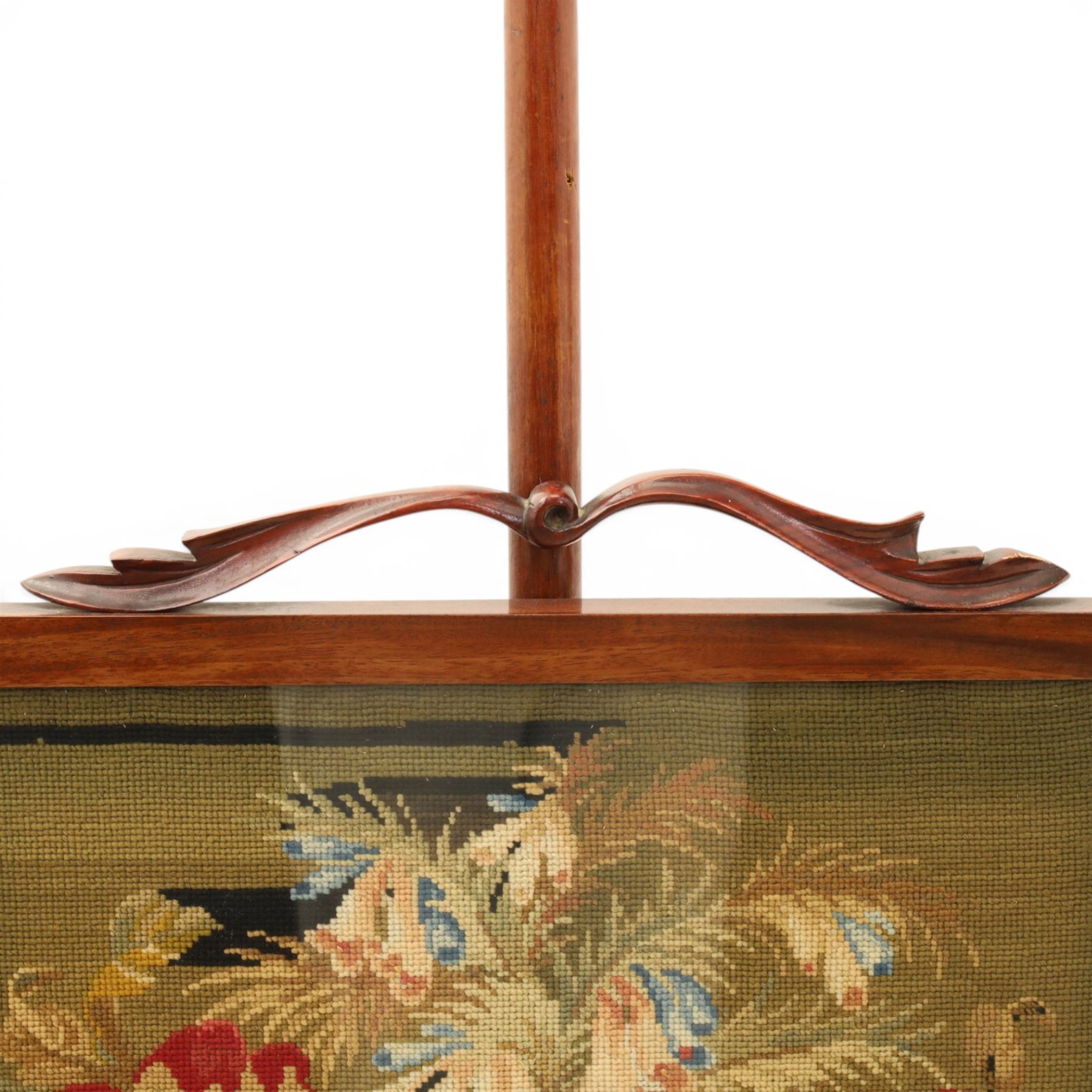 Two Victorian fire screens, comprising mahogany pole screen with glazed floral woolwork panel on turned support and triform base (H 142cm, W 48cm); and a larger carved walnut tapestry fire screen, glazed panel depicting a domestic interior scene, scroll carved cresting, barley twist uprights and turned stretcher base (H 75cm, W 49cm)