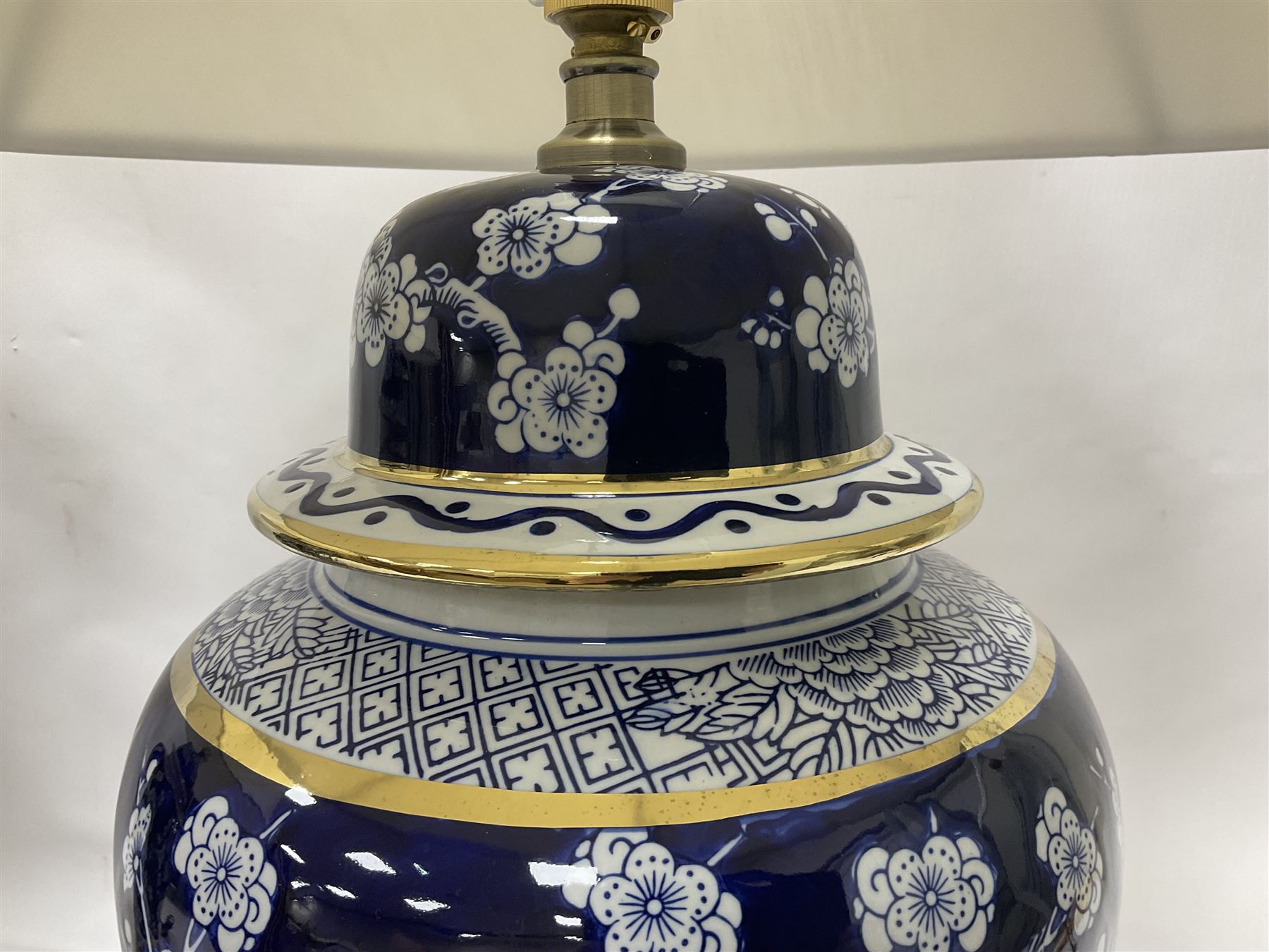 Pair of blue and white table lamps, each of baluster form, decorated with prunus blossom, within stylised borders, raised upon circular gilt base, excluding fittings H48cm