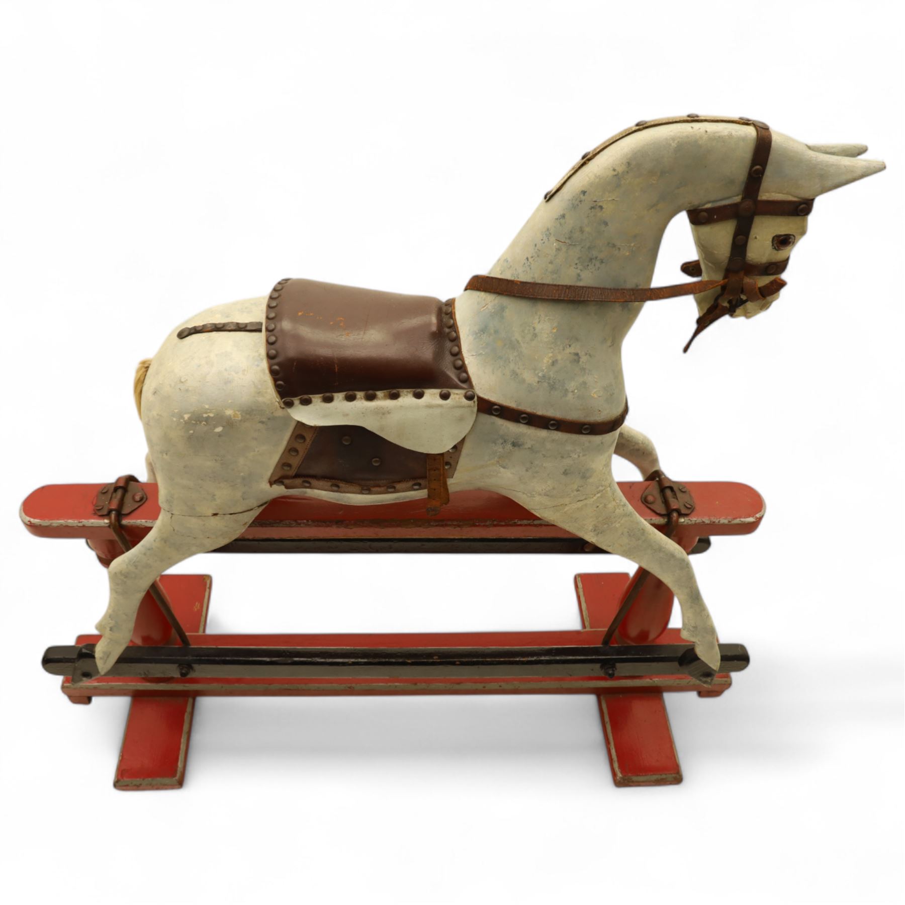 20th century carved and painted rocking horse, with original dappled paint finish, studded leather saddle and reins, on later red and black swing frame