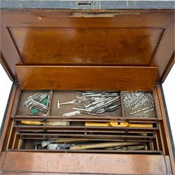 20th century black painted camphorwood lined tool chest, rectangular hinged lid over moulded edge, black painted exterior with iron straps and carry handles, the interior fitted with sliding lidded trays and drawers with turned handles, containing an assortment of hand tools