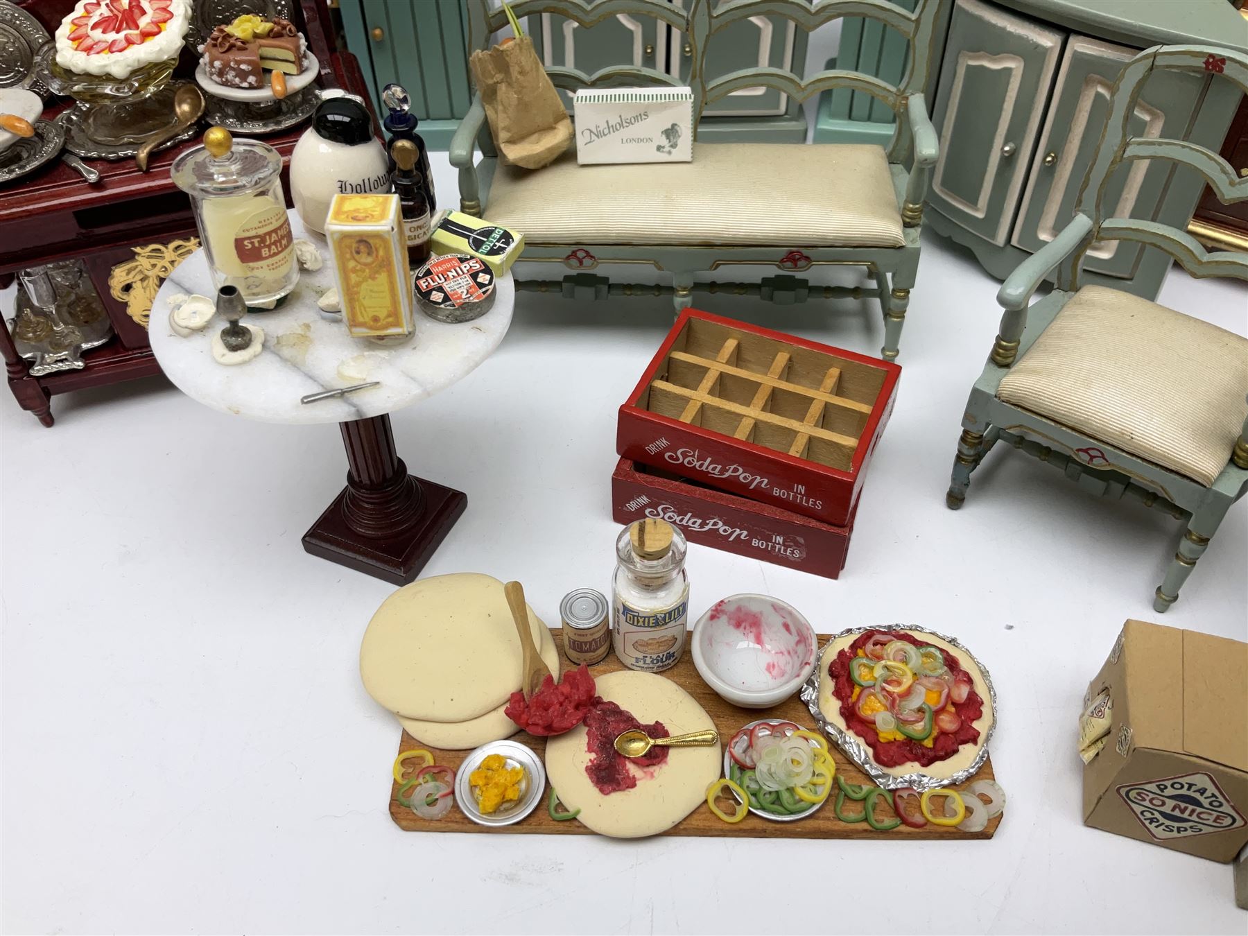 Collection of miniature dolls house furniture, to include display cabinet with pink and white floral dinner service, two serving trolleys with cakes and sweets and two blue painted kitchen dressers, together with miniature dolls house cardboard food packaging and animal figures including dogs and cats, etc