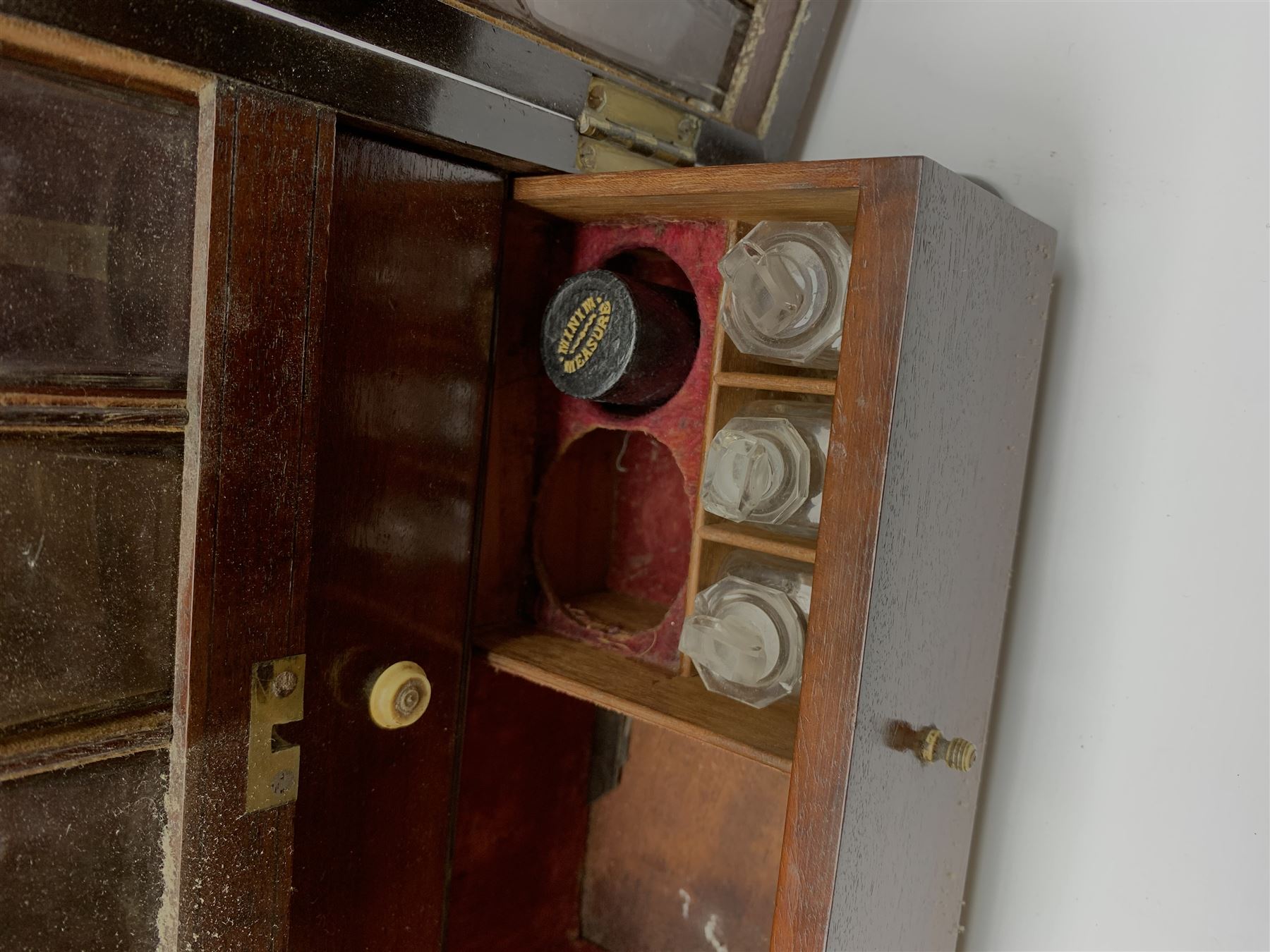 19th century mahogany travelling apothecary cabinet, with recessed brass carry handle to top, and two deep-section hinged doors to the front opening to reveal a fitted interior with clear glass bottles and two drawers, H27cm