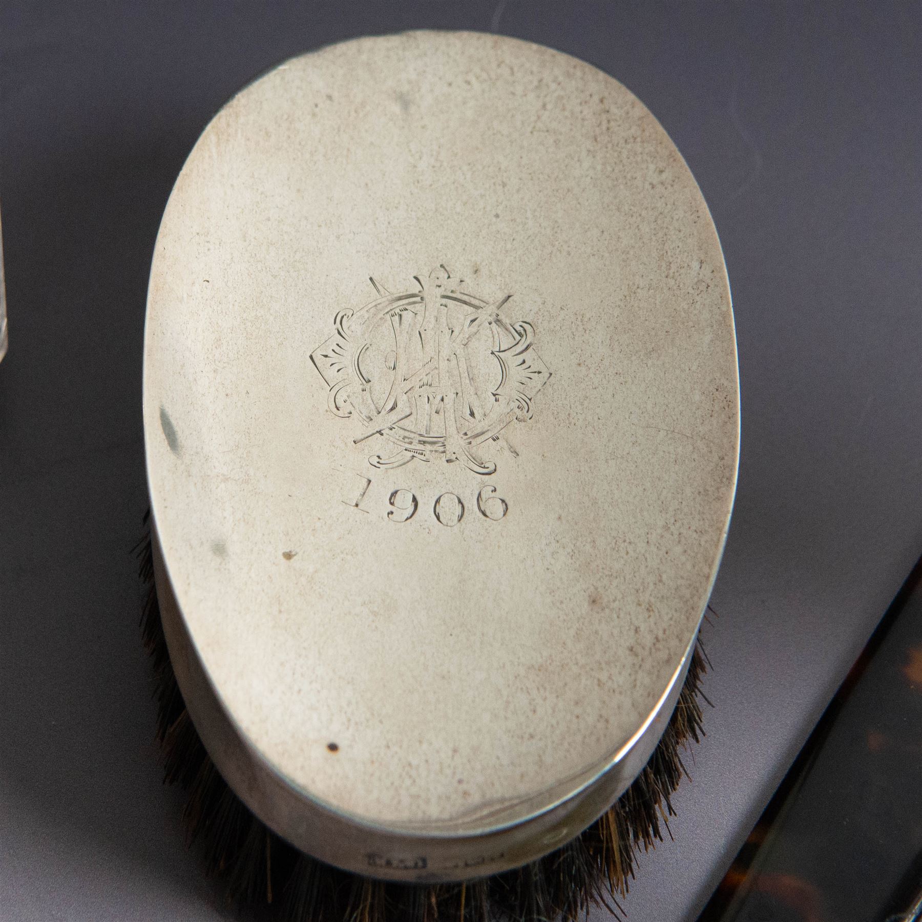 Edwardian tortoiseshell page turner with silver handle, hallmarked Birmingham 1906, maker's mark worn and indistinct, together with a pair of Edwardian silver mounted horsehair brushes engraved with monogram, and two faceted glass jars with silver lids and applied initial N to covers, all hallmarked 