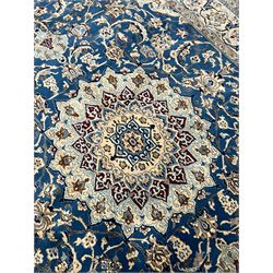 Persian Kashan blue ground rug, central floral rosette medallion within a field of swirling branches and palmettes, the border with trailing pattern interspersed with stylised plant motifs