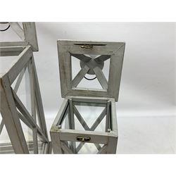 Two wooden lanterns with four glass sides, loop handles and open tops, largest example 58cm