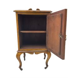 Edwardian Art Nouveau walnut bedside cabinet, raised broken swan neck back with carved flower heads, single fielded panelled door enclosing single shelf, raised on cabriole supports with ceramic castors