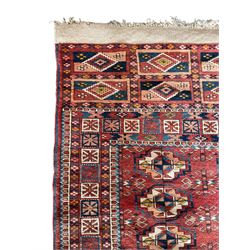 Persian Bokhara terracotta ground rug, the field decorated with six rows of repeating Gul motifs, geometric design border with rectangular repeating end panels 