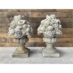 Pair of cast stone garden wall or gate finials depicting Fruit Piers, raised on separate circular squat column with plinth base