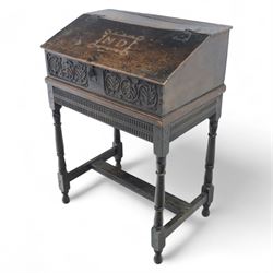 18th century carved oak Bible box on stand, the sloping lid with incised initials ‘MD’ and iron strap hinges, the front carved with stylised leaf and scroll panels enclosing central iron lockplate, on stand with gadrooned frieze, turned legs and plain stretchers