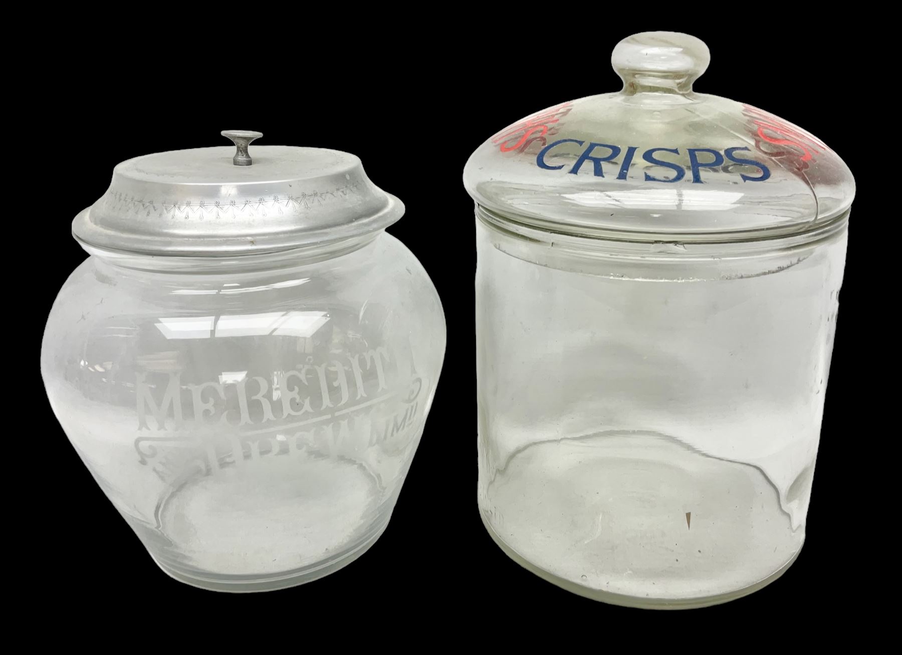 Early 20th century Meredith & Drew shop advertising glass biscuit barrel, the body of tapering form with etched lettering with original aluminium lift off lid, together with a Smith's Crisps glass jar and cover with red and dark blue letterin, tallest H25cm (2)