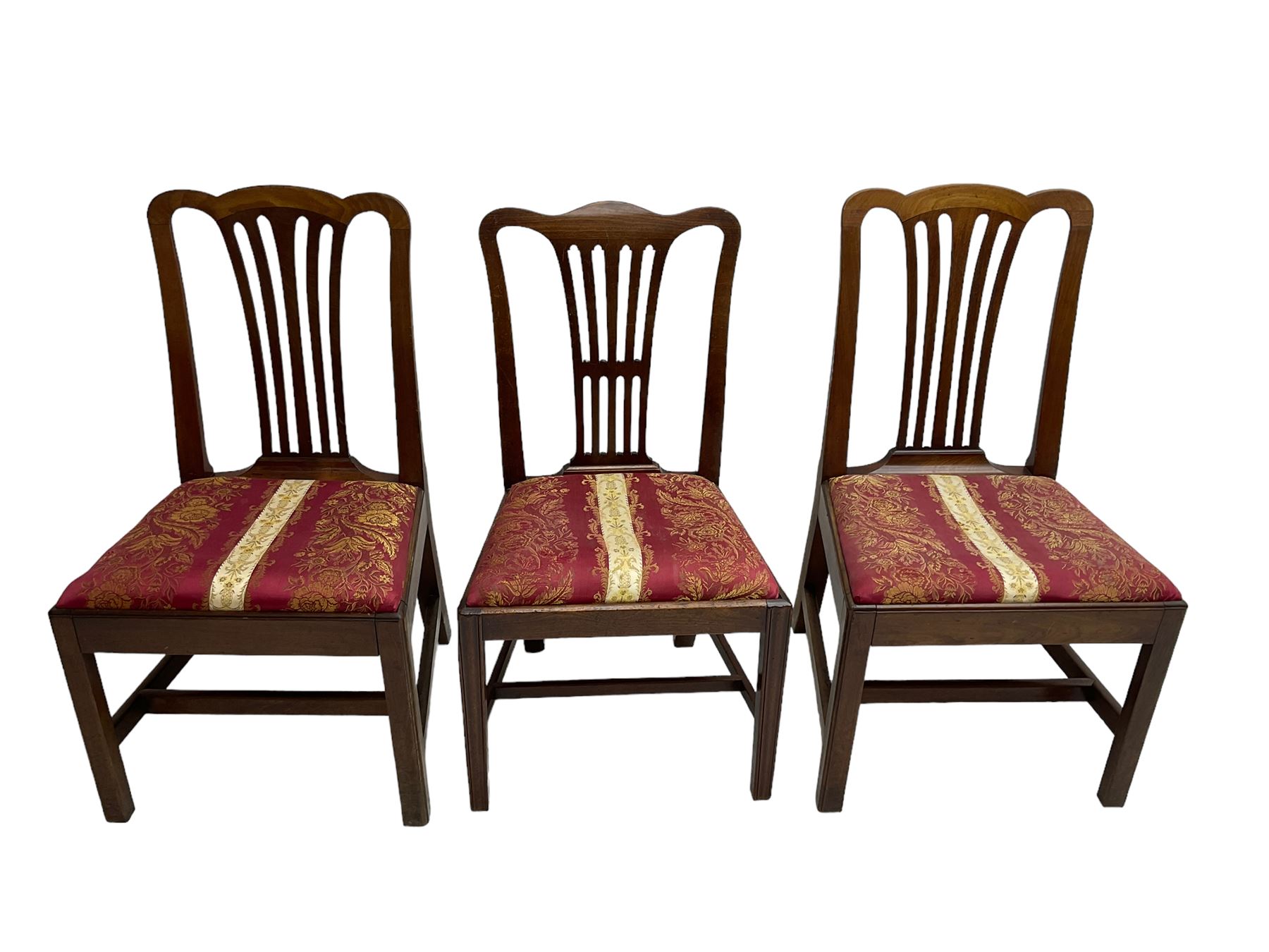Set of six (5+1) George III mahogany dining chairs, shaped cresting rail over pierced and flared splat, drop-in seat upholstered in crimson and ivory floral patterned fabric, raised on chamfered square supports united by H-stretcher