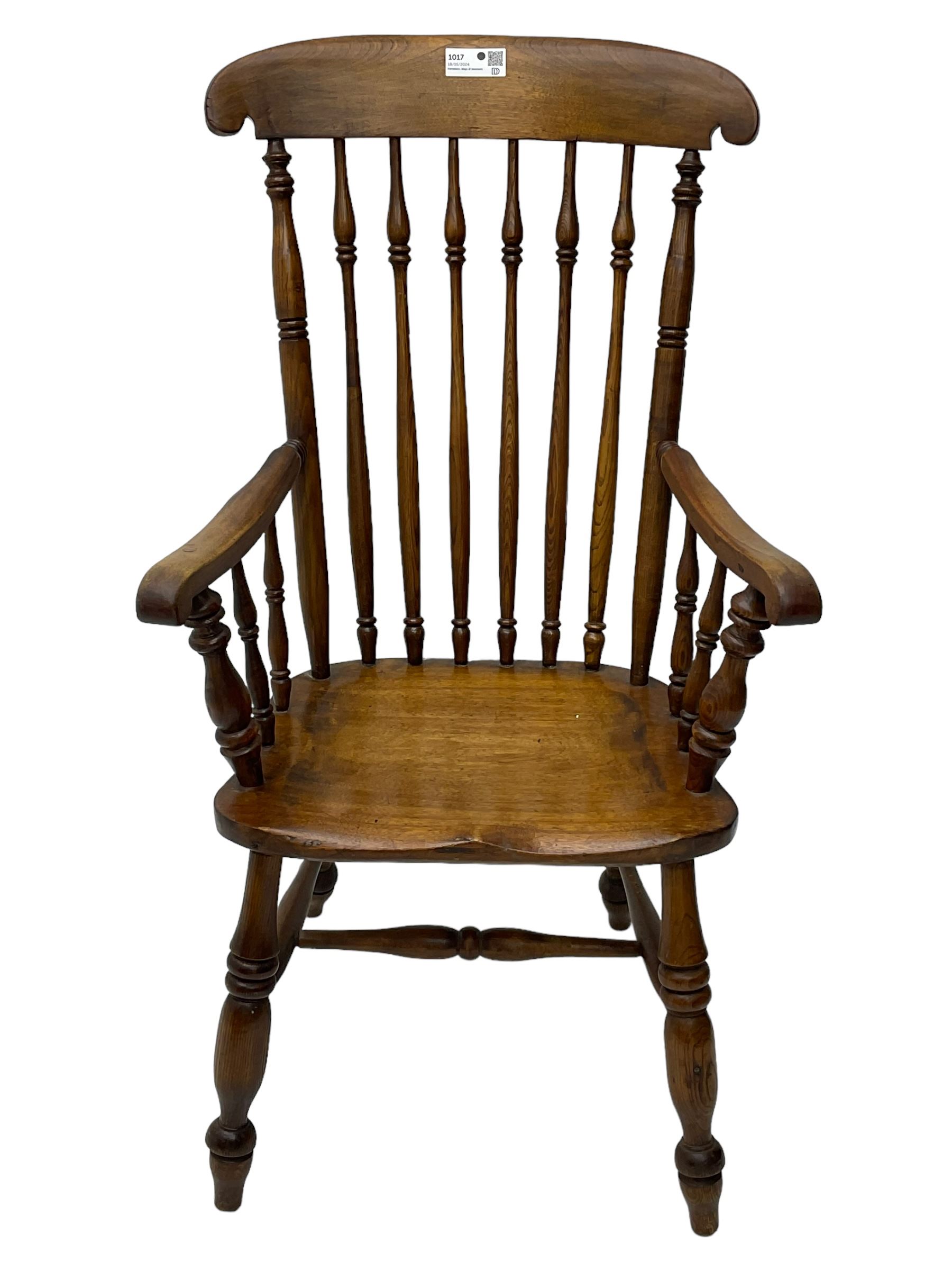 Early 19th century elm farmhouse armchair, the shaped eared cresting rail over tall spindle back, dished seat on turned supports united by H stretchers