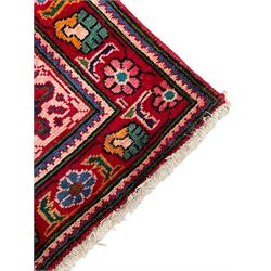 Persian Azerbaijan crimson ground rug, the field decorated with central floral motif and surrounded by trailing floral branches, enclosed within a shaped outer band with further floral decoration, the border with repeating flower heads, geometric guard stripes 