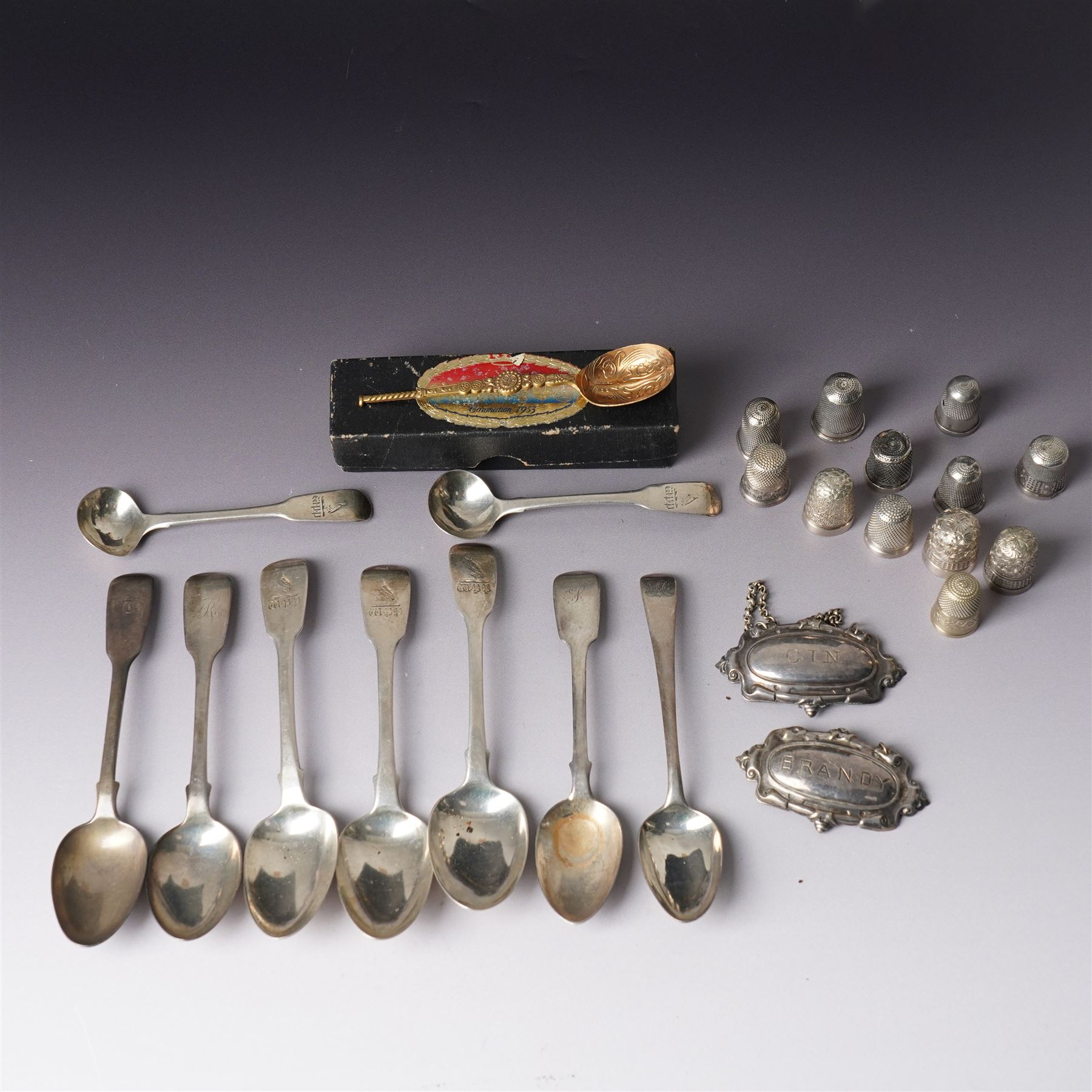 Three George IV silver fiddle pattern teaspoons London 1824, pair of George IV silver condiment spoons, four various silver teaspoons, three Charles Horner thimbles, three other silver thimbles, plated thimbles, two plated decanter labels and a plated Coronation spoon