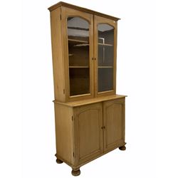 Victorian polished pine bookcase on cupboard, two glazed doors above two panelled cupboards