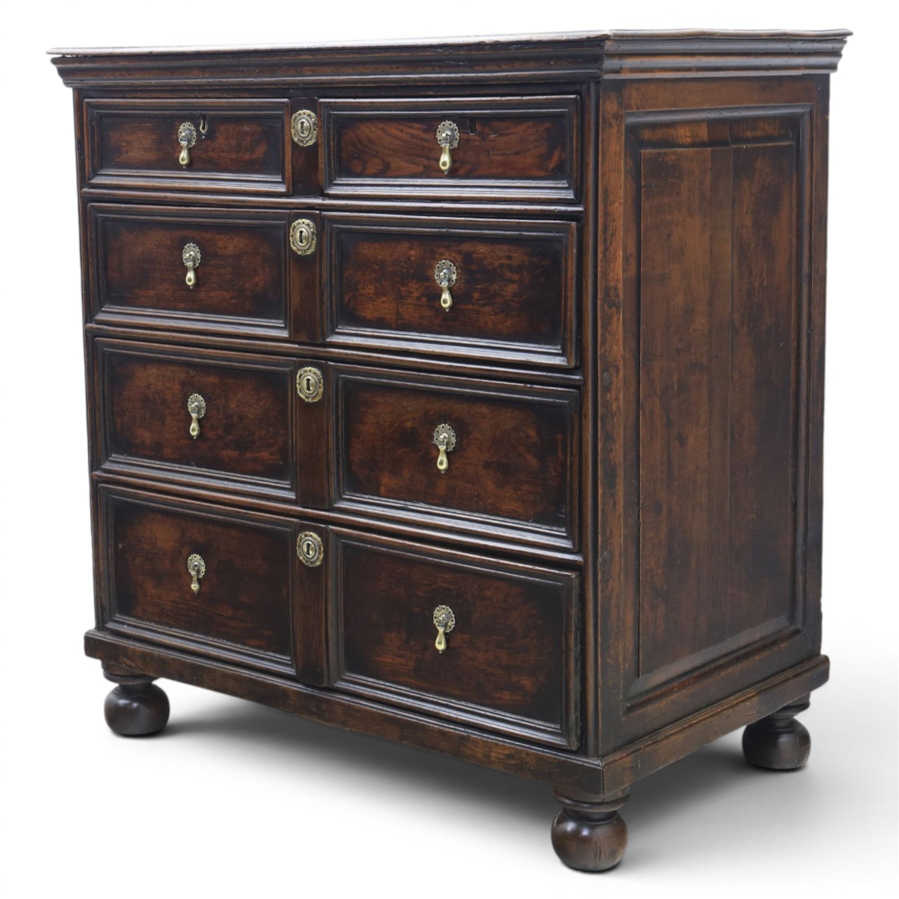 Late 17th century moulded front oak chest of drawers, rectangular plank top. above two banks of four graduated drawers, central escutcheons and drop handles, on squat bun feet
