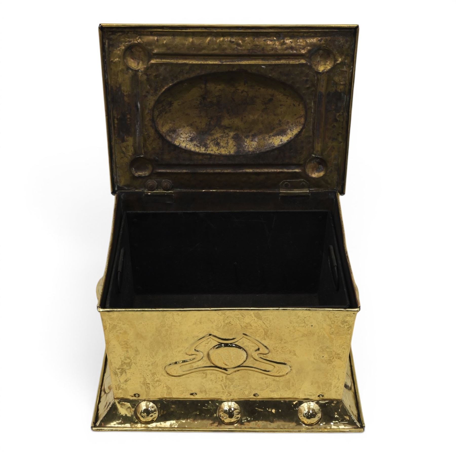 Art Nouveau brass coal box, the hinged rectangular cover embossed with a foliate design, hammered panelled sides with shaped carrying handles, on projecting plinth base with applied roundels