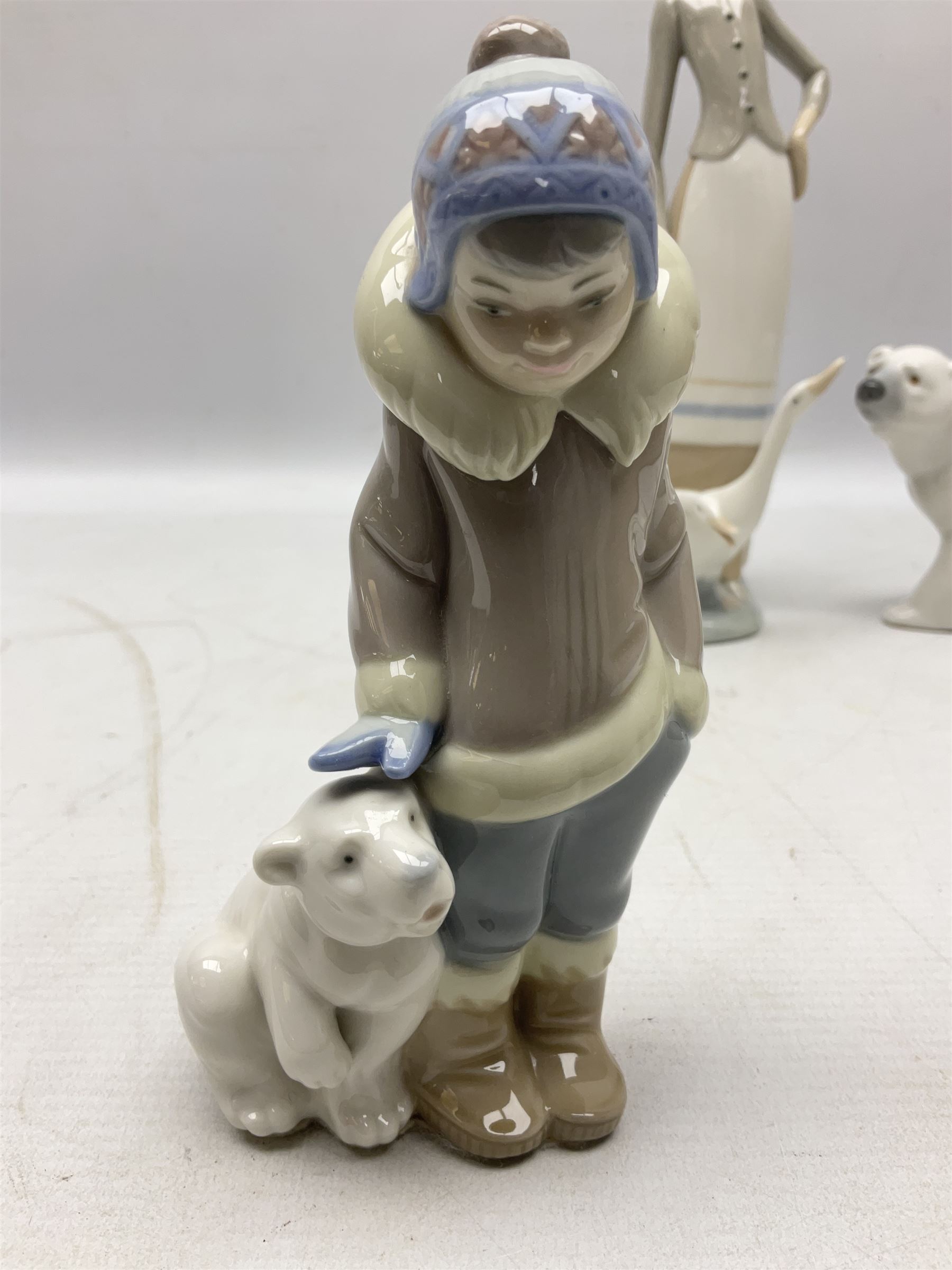 Seven Lladro figures, comprising Playful Puppy no 9135, Platero and Marcelino/Boy Hugging Donkey no 1181, Mini Seal Family no 5318, Attentive Polar Bear no 1207, Seated Polar Bear no1209, Eskimo Boy with Pet no 5238 and Girl with Geese no 1035, together with Nao goose