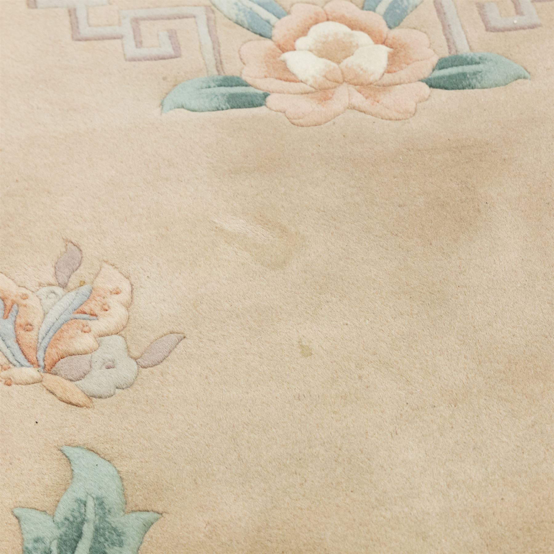 Chinese wool rug, beige ground decorated with peonies, flowering branches and butterflies, centred by a shou symbol within key pattern surround, cream border with floral sprays and double happiness motifs, cotton fringe ends