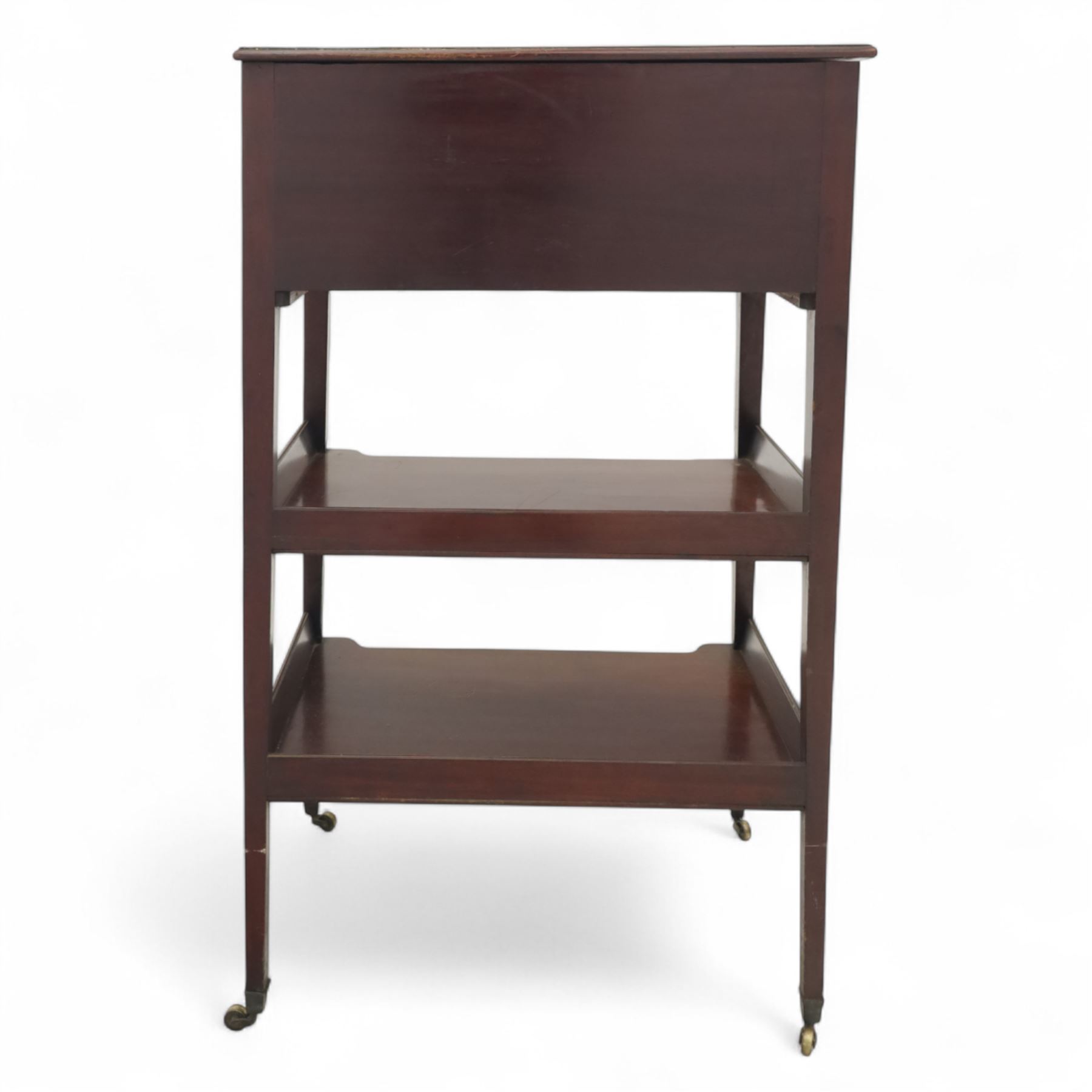 George III mahogany and boxwood-strung drawing table, the rectangular sloping reading surface with rest and oak stay, above a blind drawer and a drawer fitted with brass ring handles, side with pull-out candleholder and inkwell compartment, raised on square-section tapered legs with brass box castors united by two galleried under tiers