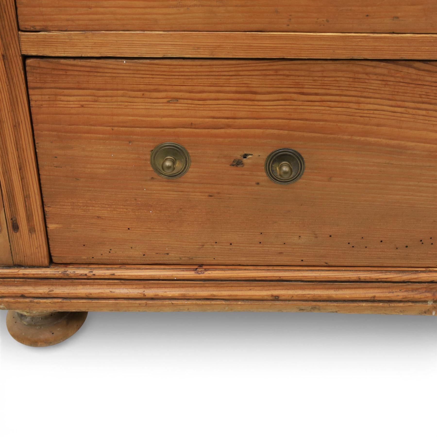 Late Victorian pine chest of drawers, the moulded top above four long drawers with brass drop handles and flower head escutcheons, flanked by pilasters, upon four turned compressed bun feet, 89cm x 103cm x 54cm