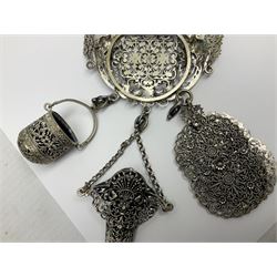 19th century continental silver plated chatelaine, the main body flanked with winged mythical beasts and central soldier slaying a dragon supporting three suspended items to include velvet lined small basket and long clasped filigree chain, together with a thimble