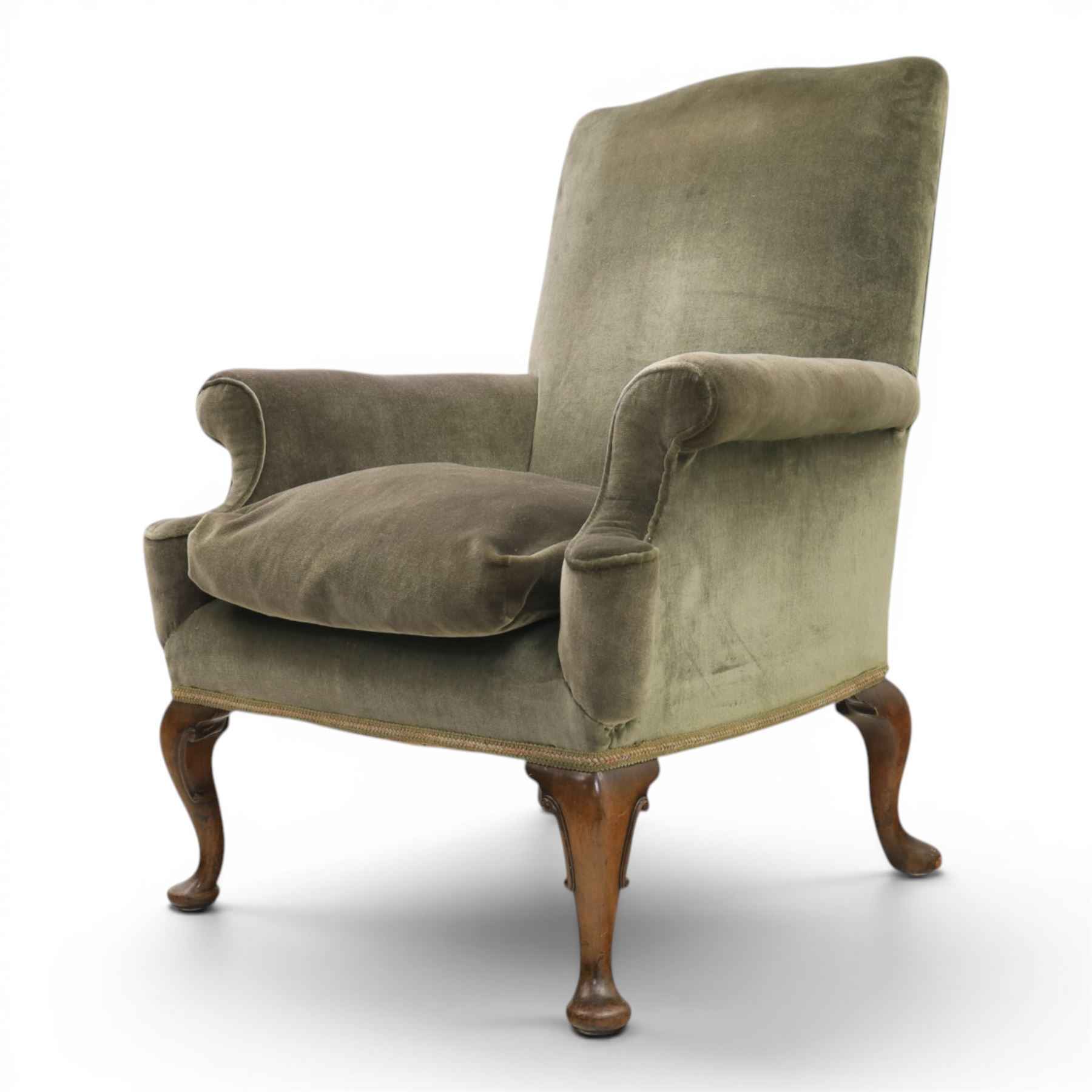 Pair of Georgian style wing armchairs, upholstered in green velvet, each with shaped wing backs, padded scroll arms and loose seat cushions, raised on cabriole supports terminating in pad feet, one with tasselled fringe