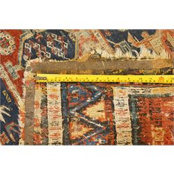 Antique Caucasian crimson ground carpet. the field decorated with three geometric indigo medallions with surrounding geometric motifs and guard lines