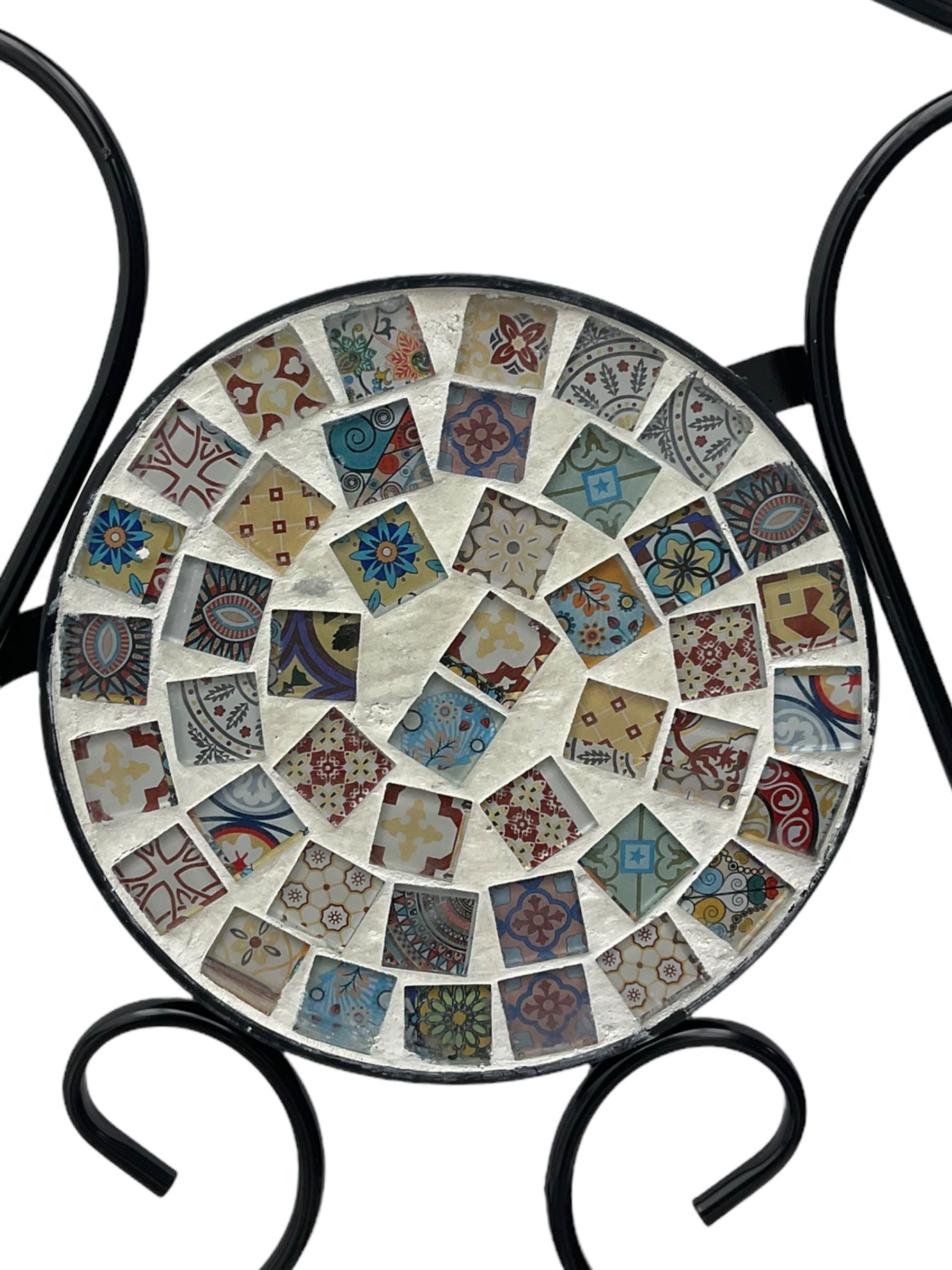 Black painted metal bistro set, circular table with mosaic top, and pair of folding chairs with mosaic panels 