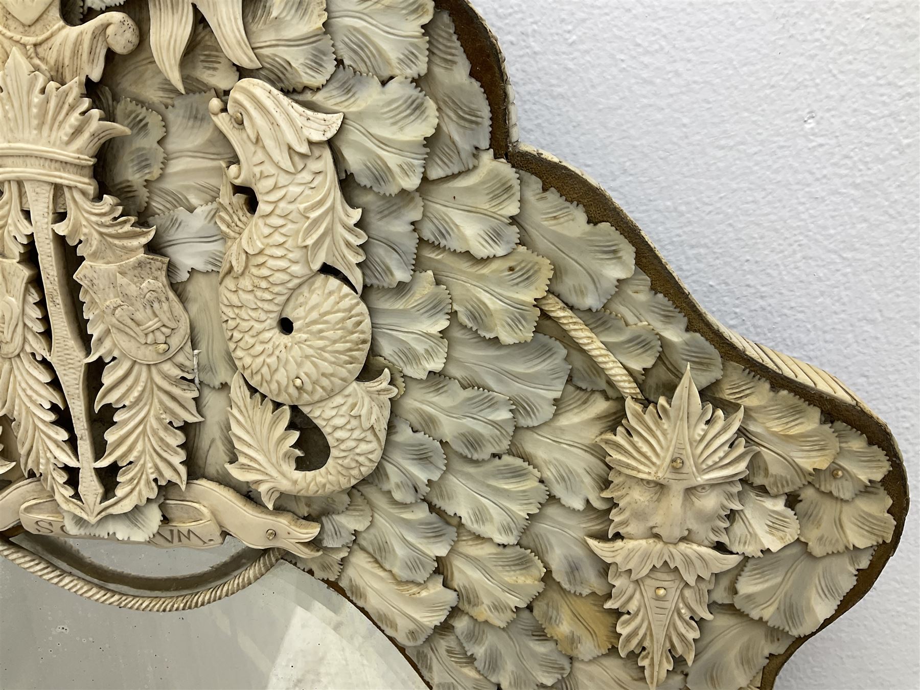 Pair 19th century French Dieppe bone and ivory wall mirrors, the oval bevelled mirror plates within rectangular frames with shaped tops, profusely decorated with ivory leaves, further detailed with carved bone armorial type crest inscribed 'SGOTORVM', putti, fish and mask heads, H81cm W48cm