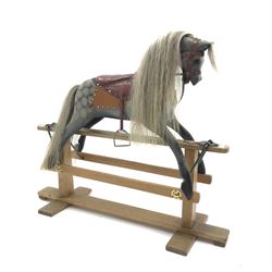 Early 20th century dapple grey rocking horse, leather rein and saddle with stirrups on trestle base