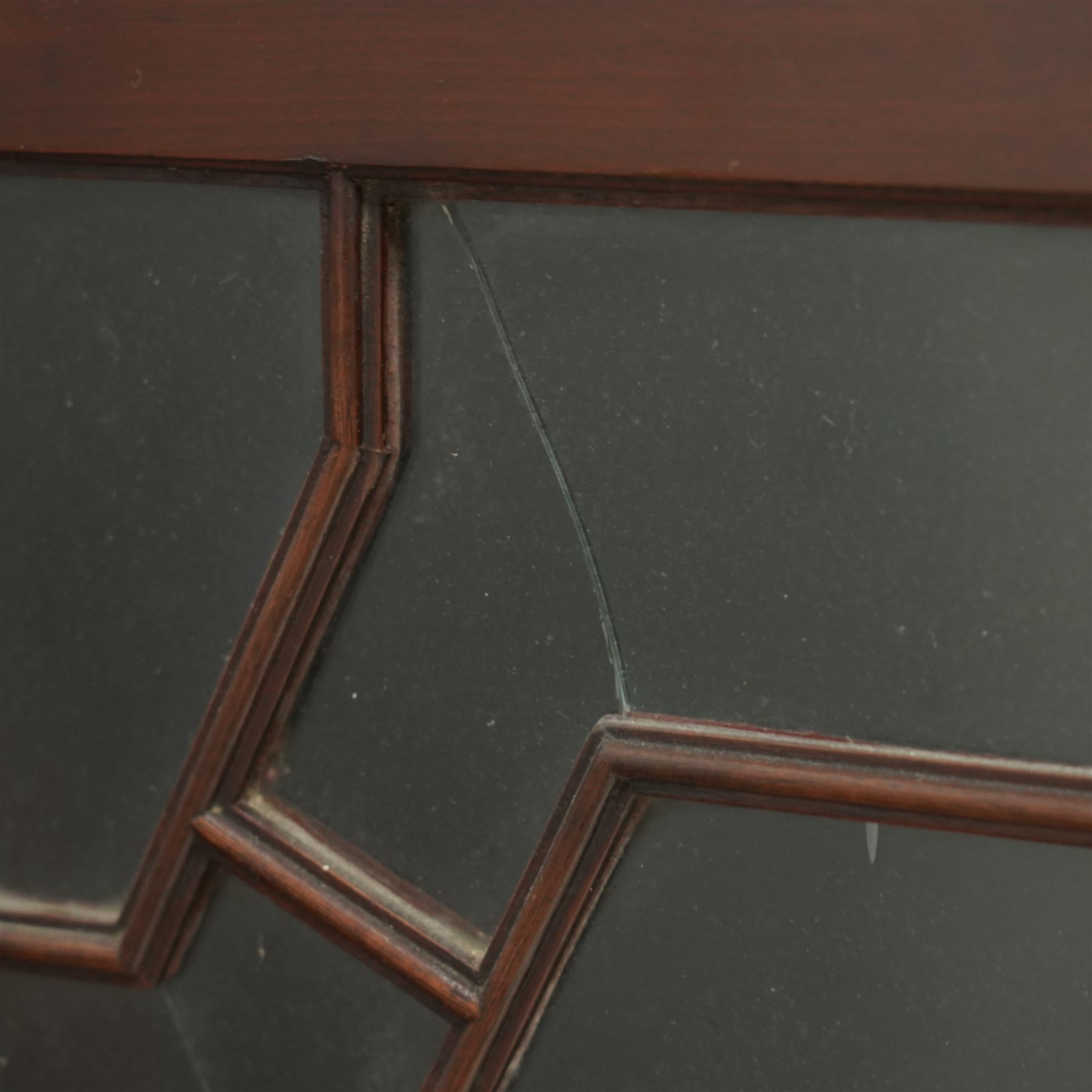 Early 20th century Chippendale design mahogany bookcase, projecting moulded cornice over four astragal glazed doors, the interior fitted with adjustable shelves, on bracket feet 