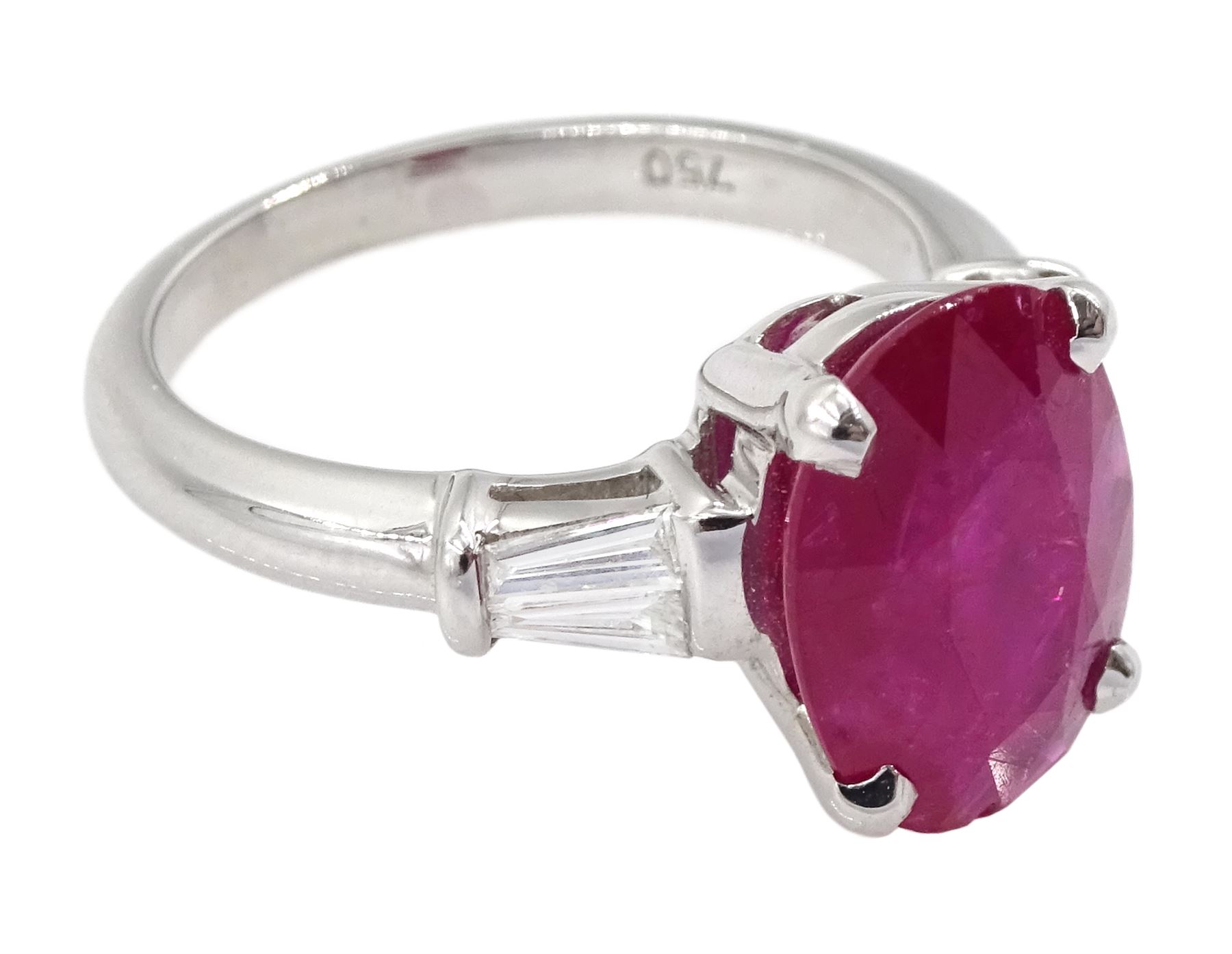 18ct white gold ruby and diamond ring, the oval cut ruby of 4.16 carat, with two tapered baguette cut diamonds set either side, hallmarked