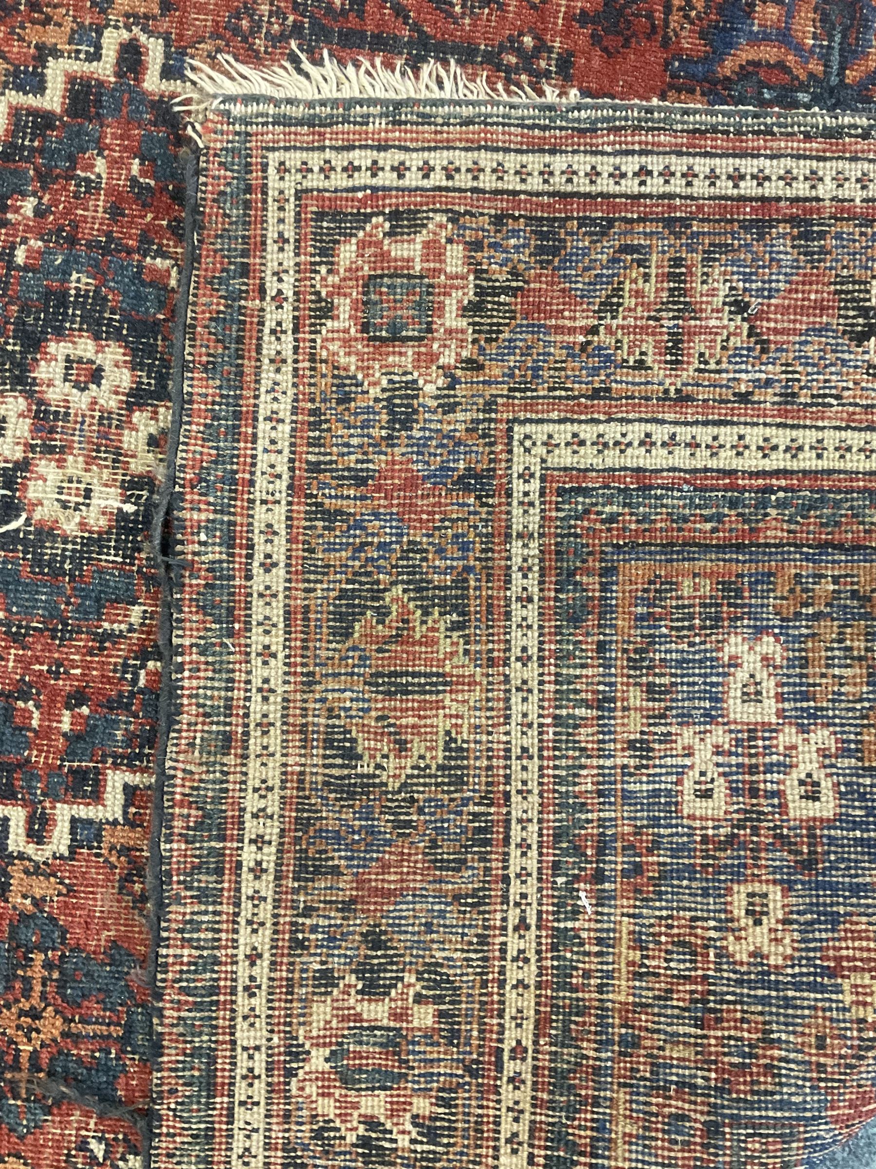 Persian Hamadan red ground rug, the field decorated with floral motifs with central lozenge medallion, guarded border decorated with repeating stylised plant motifs