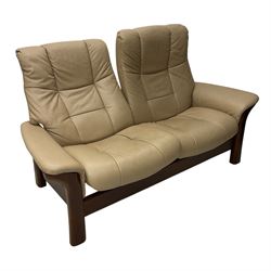 Ekornes Stressless - two-seat beech framed sofa, upholstered in beige-brown leather with stitched panel detailing, featuring curved armrests and high back supports with manual recline mechanism, raised on a dark-stained beech frame with sculpted supports