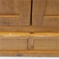 Contemporary pine hanging wardrobe, twin panelled doors enclosing open hanging space with brass rail, two drawers to lower section, on moulded plinth base