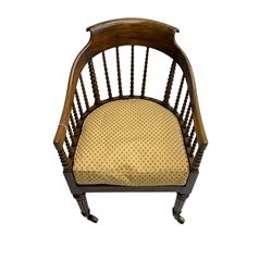 William IV rosewood tub armchair, the arched bow cresting rail over graduated bobbin turned spindles, cane seat with loose cushion, terminating in brass cups and castors.