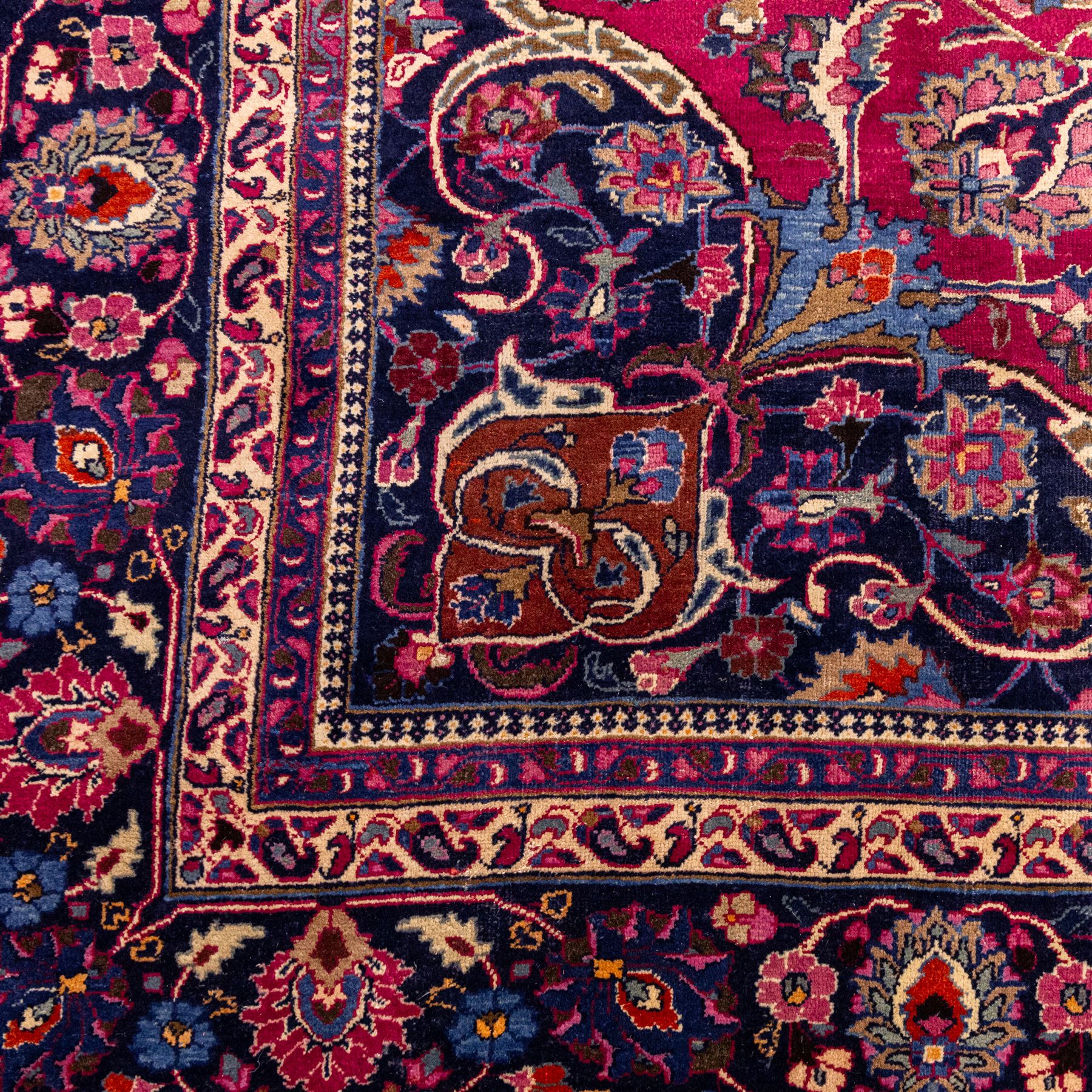 North East Persian Mashad hand-knotted carpet, rich madder red field with central cusped foliate medallion with issuing scrolling arabesques, palmettes, and floral sprays, enclosed within a broad indigo main border of bold palmettes, between multiple guard stripes, with cotton fringe ends 