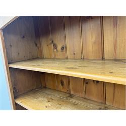 Early 20th century pine kitchen dresser, featuring a hutch with arched top over three open shelves, the base with five drawers over three cupboard doors, turned column supports flanking the doors, scalloped apron base with bracket feet