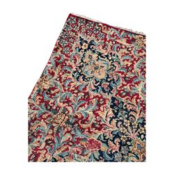 Persian Kirman carpet, the bold ruby field hosting a multi-lobed central medallion, embellished with scrolling vines and floral sprays, edged by layered borders and trimmed with short fringe