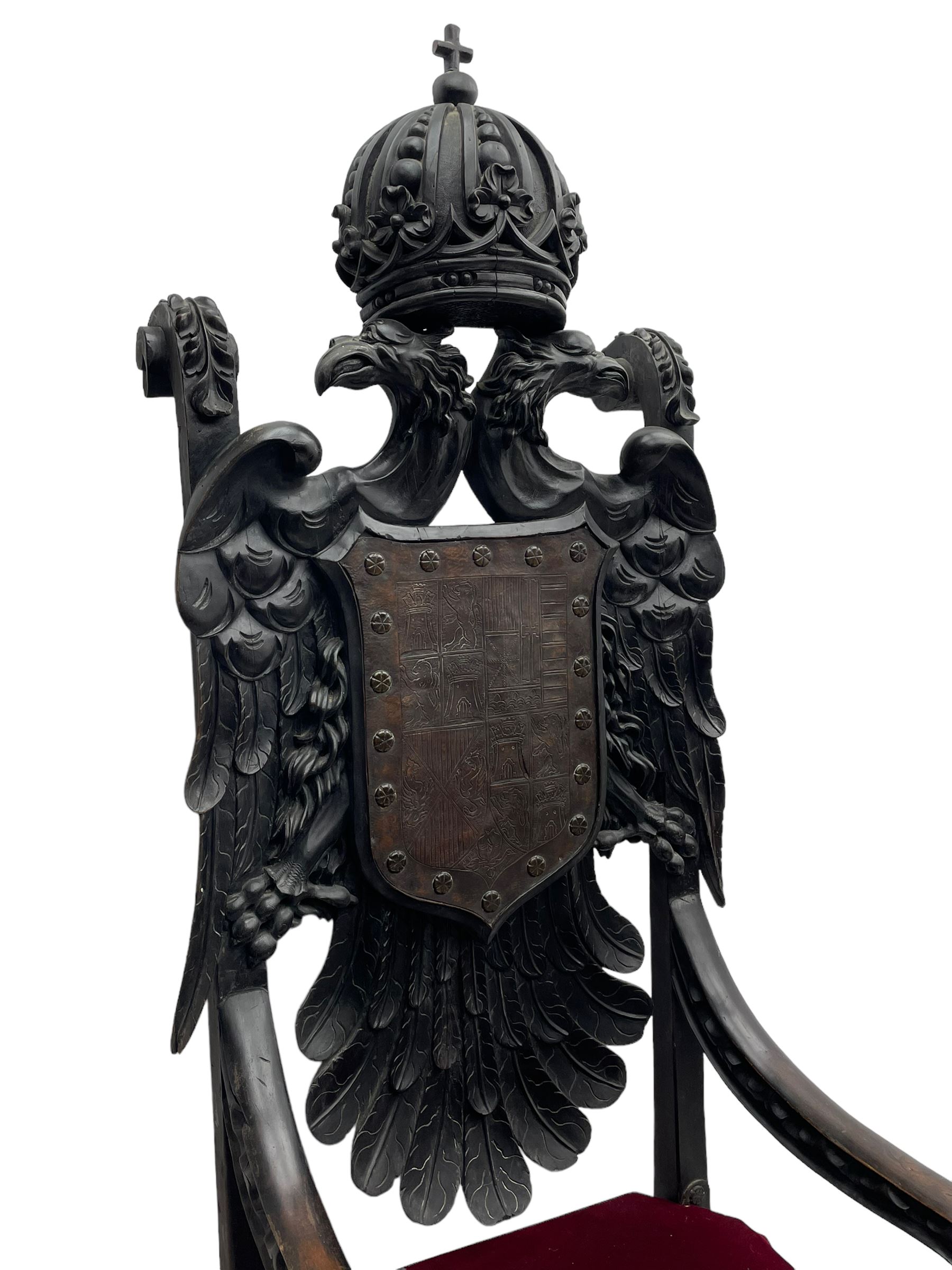 Grand mid-to-late 19th century heavily carved beech framed throne chair, the crown pediment carved with flower heads and cross finial, scroll and acanthus carved upright supports with twin perching griffin back enclosing etched leather work heraldic shield with castle and lion motifs over splayed feathers, flower head carved down sweeping arms with grotesque carved terminals, the seat rails carved with further flower heads on moulded supports with oversized ball and claw carved feet

Provenance: A very similar chair was used in the filming of Stanley Kubrick's 'Eyes Wide Shut' (1999)
