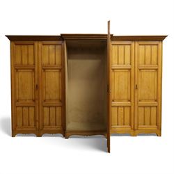 Gothic revival ash breakfront wardrobe in the manner of Charles Bevan, the four fielded panelled doors flanking a central mirrored door, opening to reveal an fitted interior with hanging rails and compartment shelves and drawers, upon a shaped plinth base with bracket cut feet

