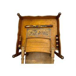 Late 19th century American oak child's metamorphic high chair and play table, carved spindle backrest with pierced splat, detachable tray with abacus and hand painted pastoral decoration, on turned supports with metal wheels