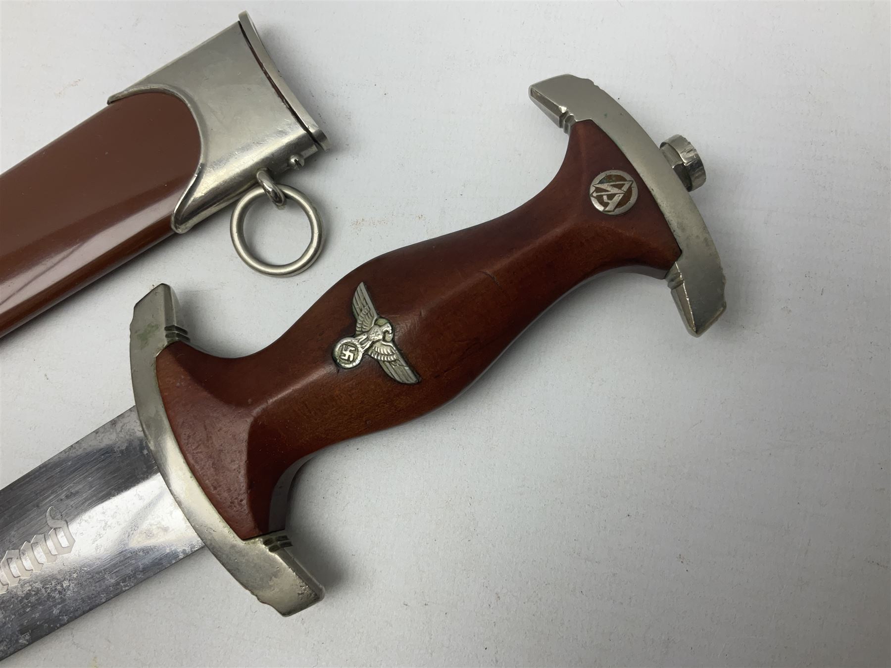 WW2 German SA dagger the 22cm double edged steel blade by G. Felix Gloriawerk Solingen inscribed 'Alles Fur Deutschland', the cross-piece impressed with the SA Gruppen mark Nm verso for Nordmark, wooden grip inset with eagle and SA emblem; in brown painted scabbard with nickel mounts L37cm overall