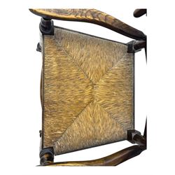 Early 19th century ash armchair, the back with winged spindles extending from a shaped top rail, above a splat of two rows of vertical spindles, with curved arms and a rush seat, raised on turned supports united by double stretchers terminating in castors