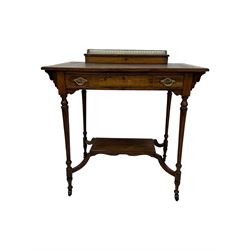 Late Victorian walnut writing table, rectangular leather-inset top surmounted by a brass gallery, fitted with a single frieze drawer, raised on turned tapering supports with lower undertier and ceramic castors