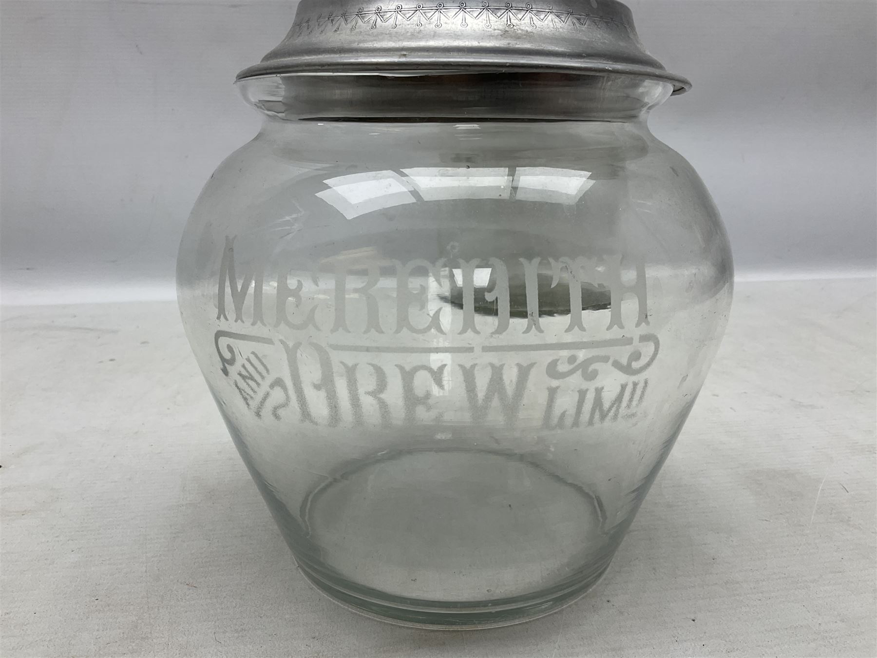 Early 20th century Meredith & Drew shop advertising glass biscuit barrel, the body of tapering form with etched lettering with original aluminium lift off lid, together with a Smith's Crisps glass jar and cover with red and dark blue letterin, tallest H25cm (2)